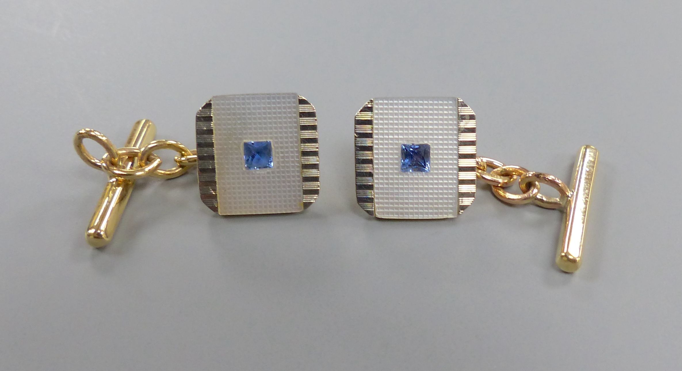 A cased pair of early to mid 20th century 18ct & 9ct, mother of pearl and sapphire set square cufflinks, 12mm,